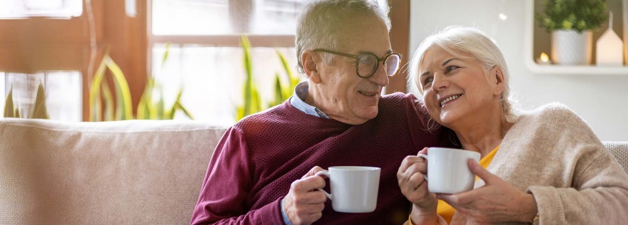 Gelukkig senior paar thuis op de bank met een kop koffie